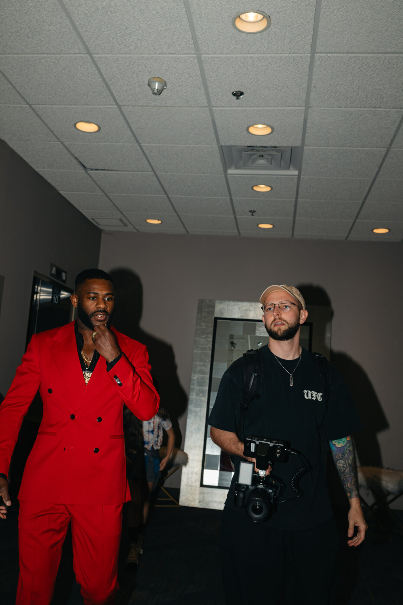 Dom Tomasello walking fight week alongside Aljamain Sterling, camera in hand